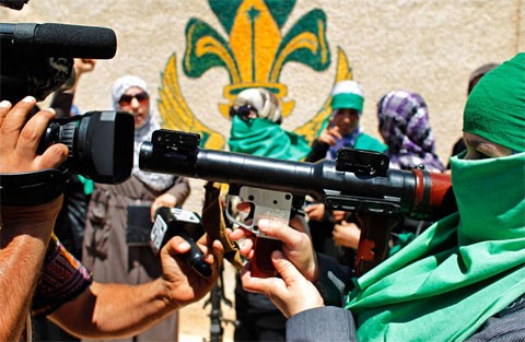 Một phóng viên quay lại cảnh một người phụ nữ Libya đang chĩa súng vào máy quay tại thị trấn Gharyan, cách thủ đô Tripoli khoảng 100 km về phía tây nam, hôm 10/7. Đây là một hoạt động nằm trong một chuyến đi do chế độ cũ ở Libya tổ chức. Chế độ Gadhafi muốn thể hiện việc vẫn kiểm soát được nhiều phần của vùng núi non phía tây Libya và quyết bảo vệ lãnh thổ trước mọi cuộc tấn công. Ảnh: AP